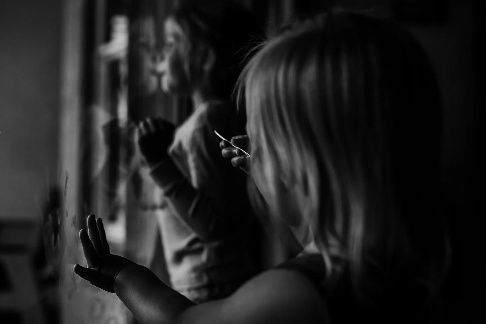 Little girls look outside sliding glass doors 