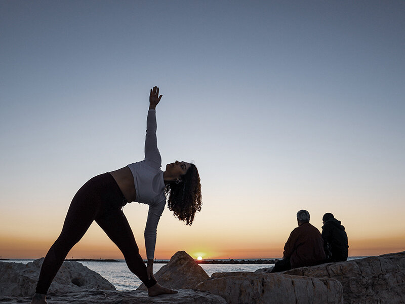 Woman does yoga at sunset