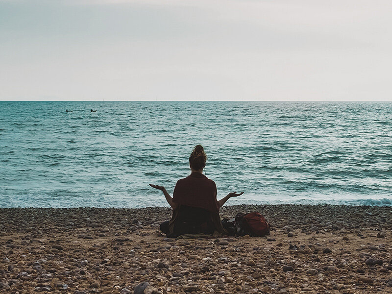 Woman meditates on the beach