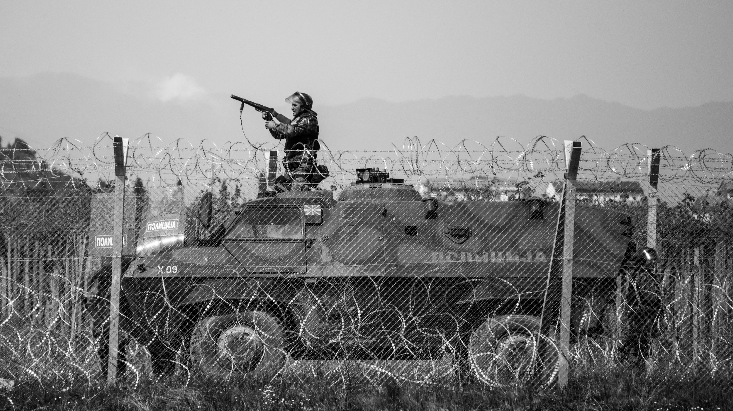 Smoke rises from the barrel of a gun, as a border guard from FYROM fires rubber bullets across the border at refugees gathered on the Greek side in Idomeni, April 2016.
