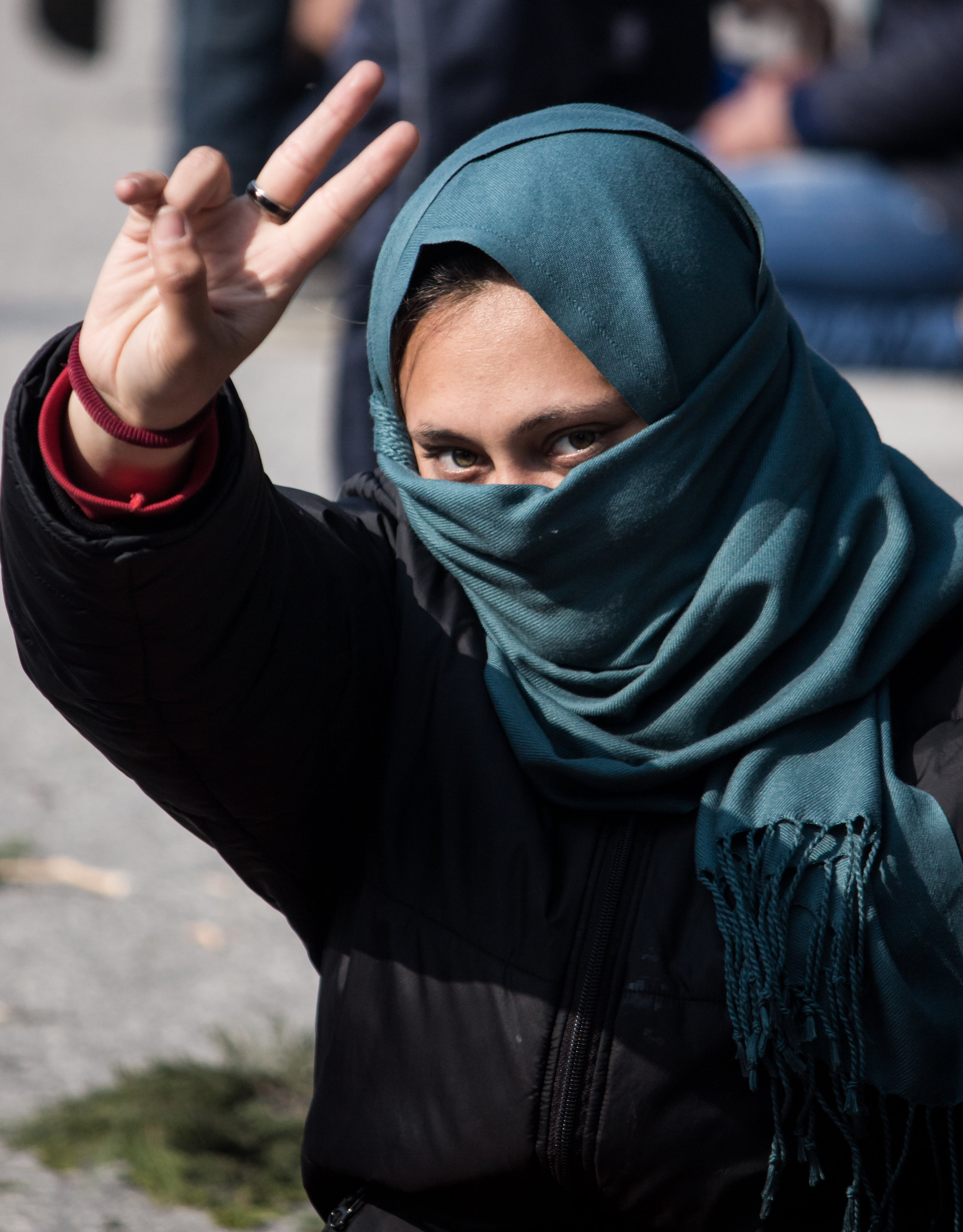 A young refugee woman holds up her hand forming the peace sign during protests in the town of Polykastro, Greece in March 2016.