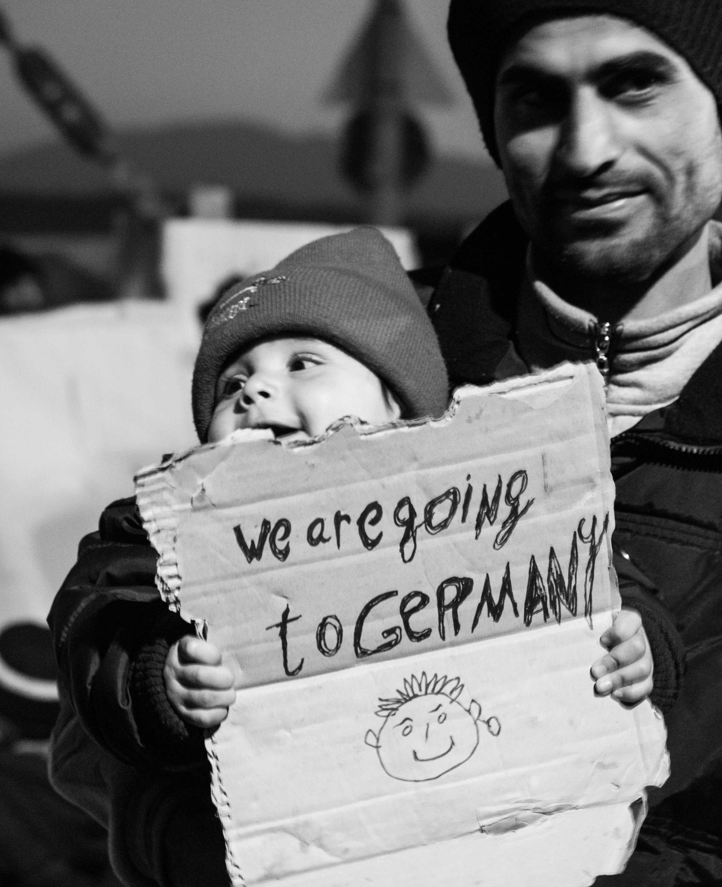 A baby holds up a sign "We are going to Germany!" in her father's arms, during a peaceful protest in the migrant settlement in Idomeni, March 2016.