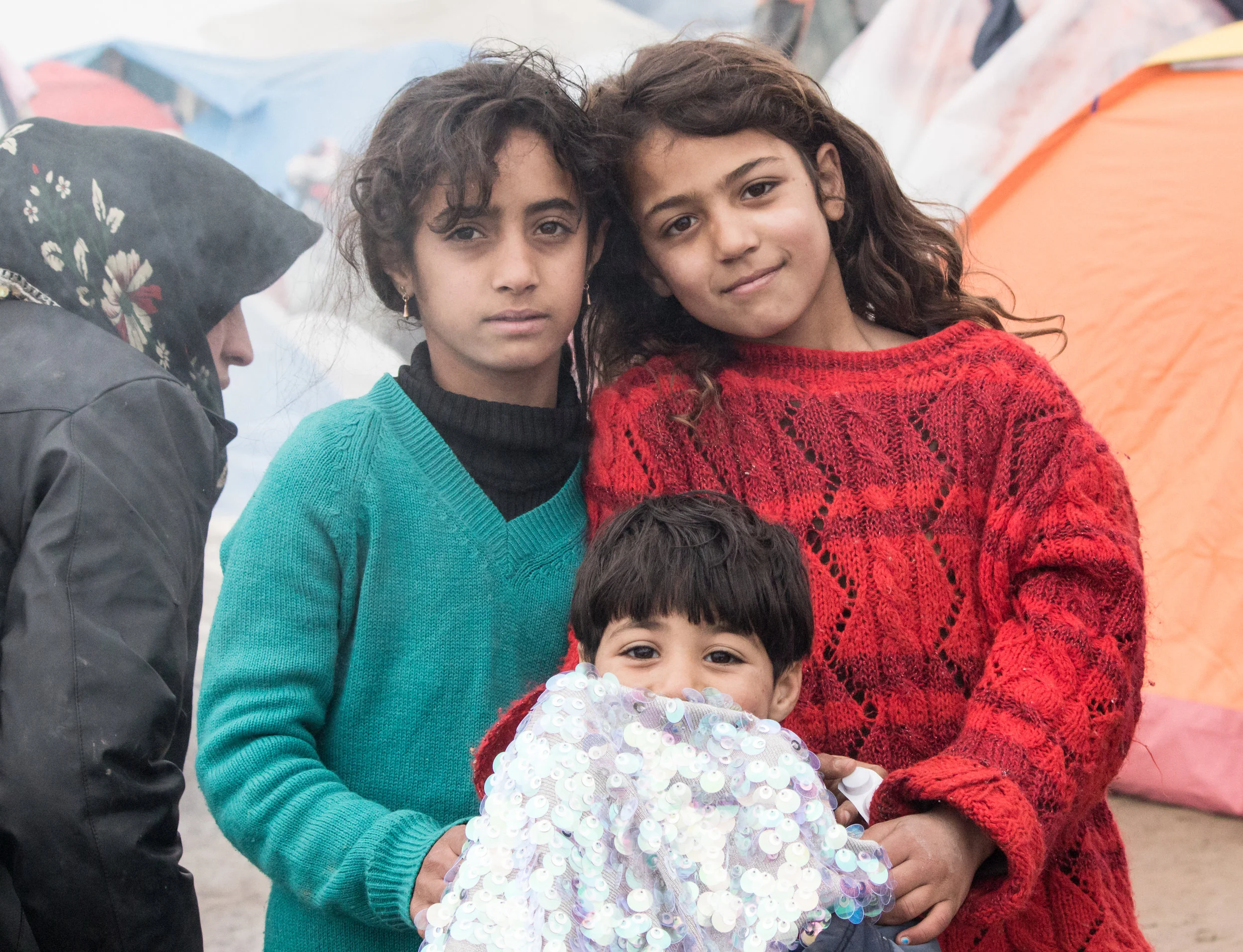A group of siblings, from Syria, pose together for a photo in the camp of Idomeni, March 2016. They were very insistent on including their sequin covered dress.