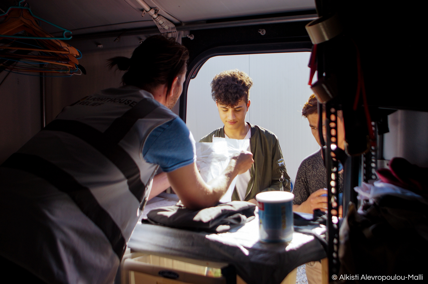 A volunteer uses a sheet of useful phrases to communicate with some young migrants at the clothes distribution point of the Stage 2 transit camp in Skala Sikamineas. People are given dry clothes, food and snacks upon arrival while they wait to be tr
