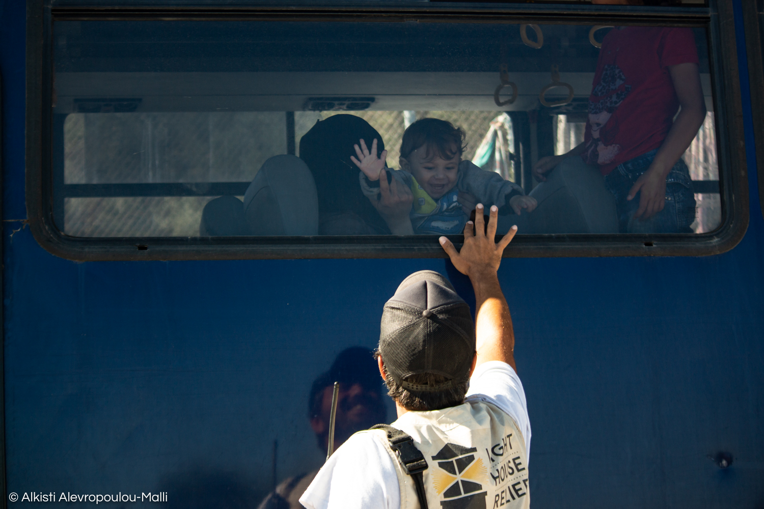 A young child and the Emergency Response Coordinator share a brief moment of goodbye before the bus leaves for the Moria detention centre.