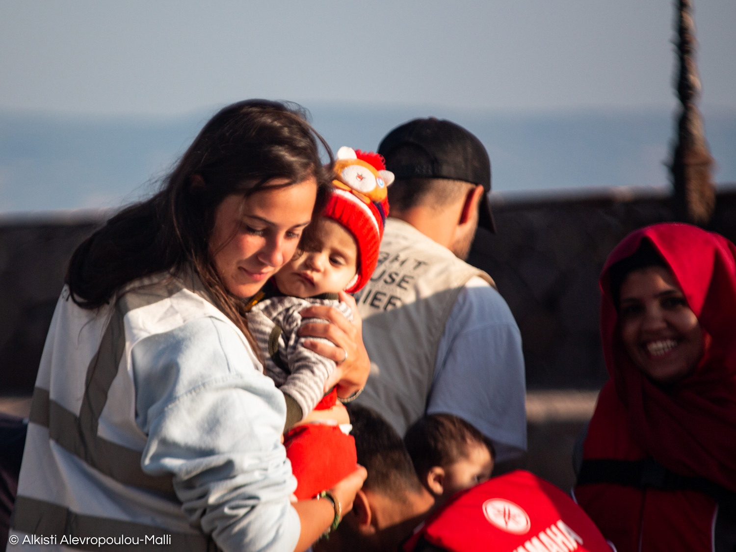 A volunteer helps carry a small child safely to shore during a disembarkation in the port of Skala Sikamineas.