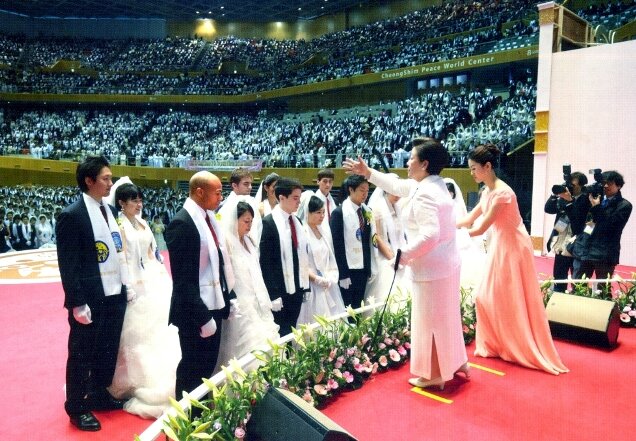 True Mother sprinkling holy water over representative couples.