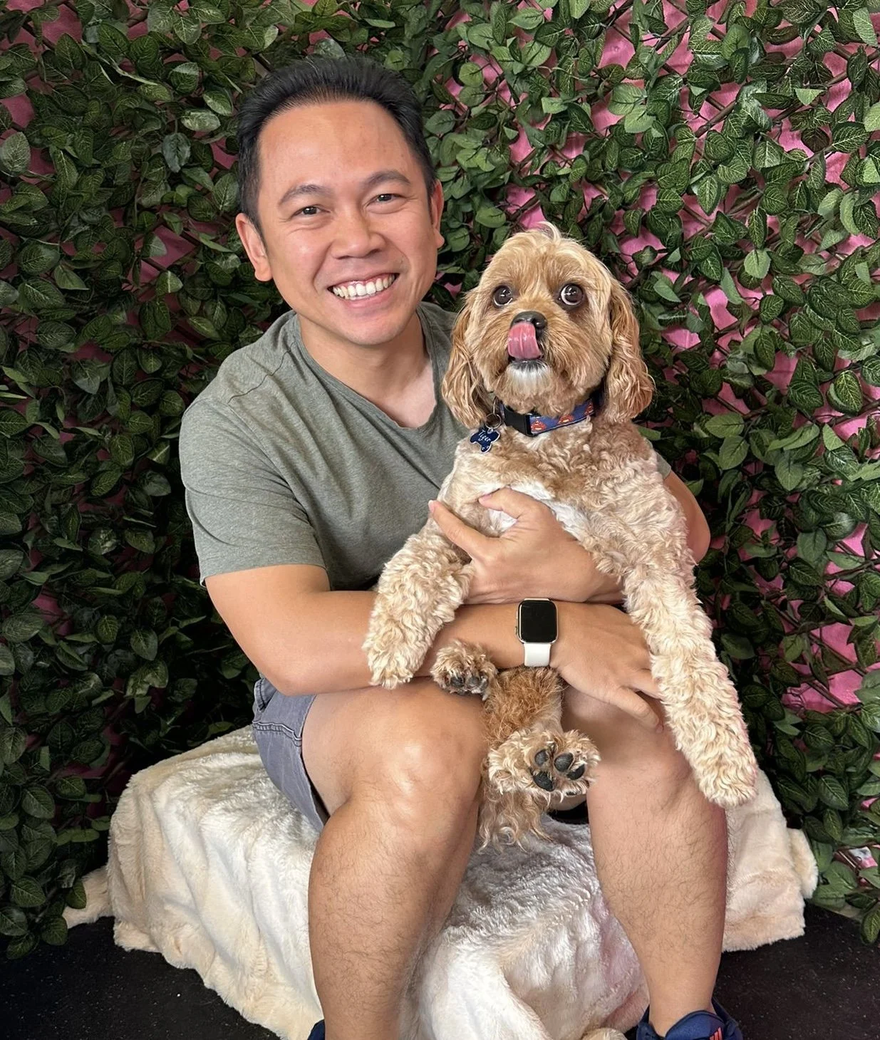 Renaldy sitting holding a cavoodle named Tiger