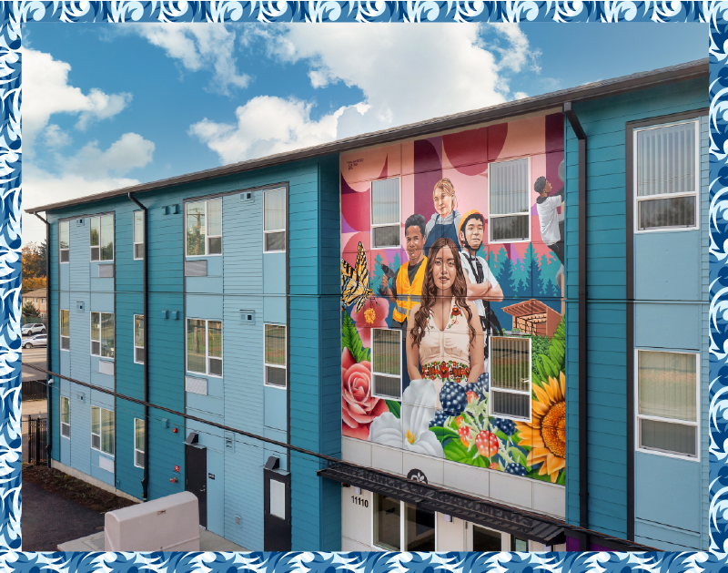 Photo of exterior of three-story apartment building painted in light blue, with a colorful mural representing area residents, flowers, and a butterfly.