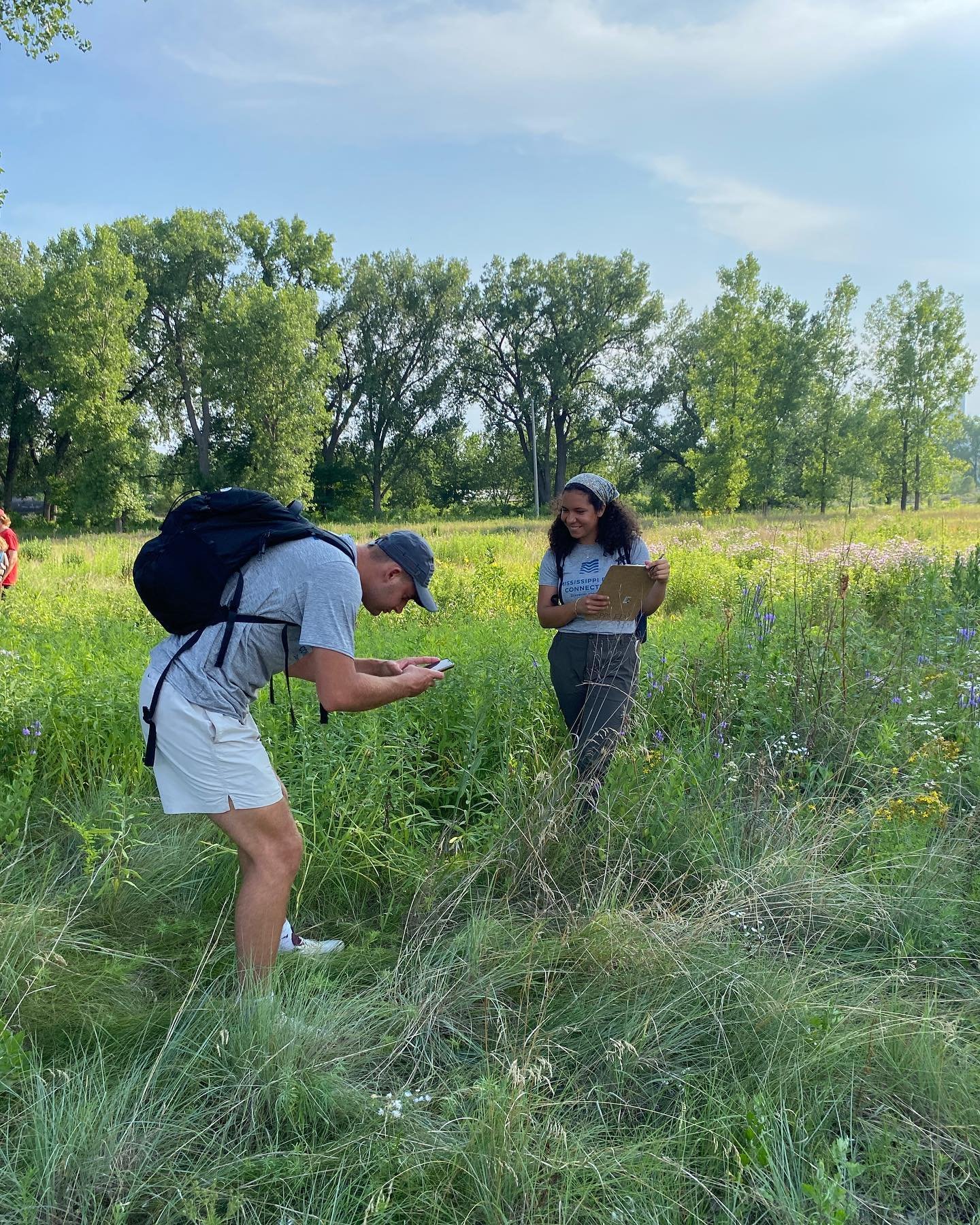  Two people stand in the grasses of a prairie and make observations about wildlife in a notebook. 
