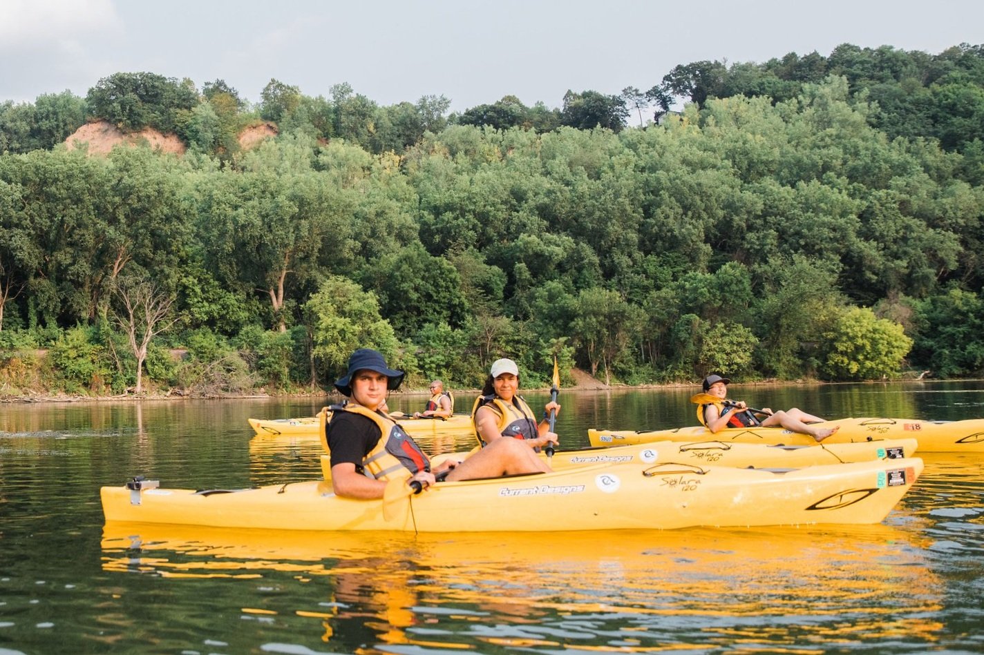  Several people paddle around a lake in yellow kayaks. 