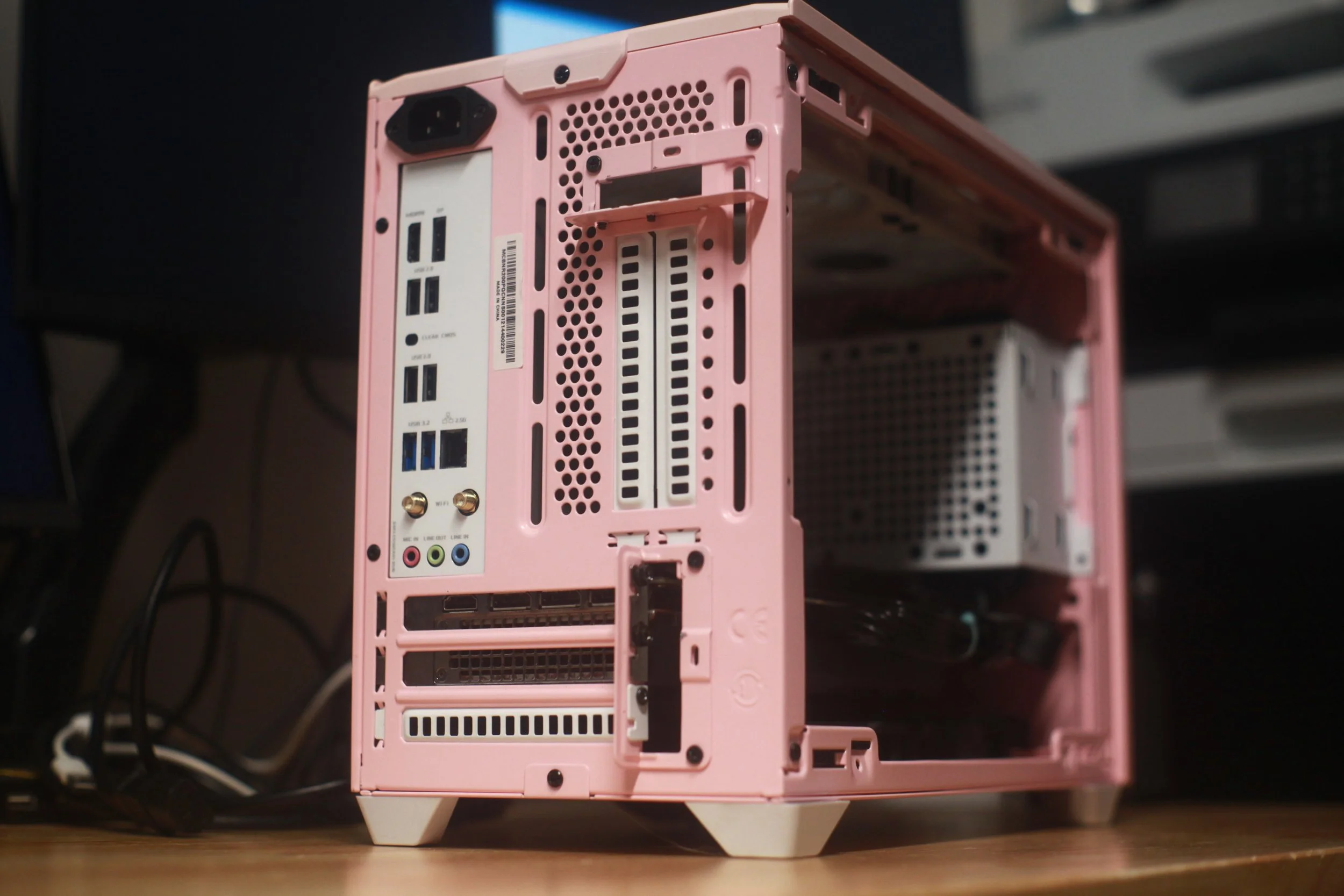Pink computer tower, side view showing ports, slots, and ventilation holes, with a black background.
