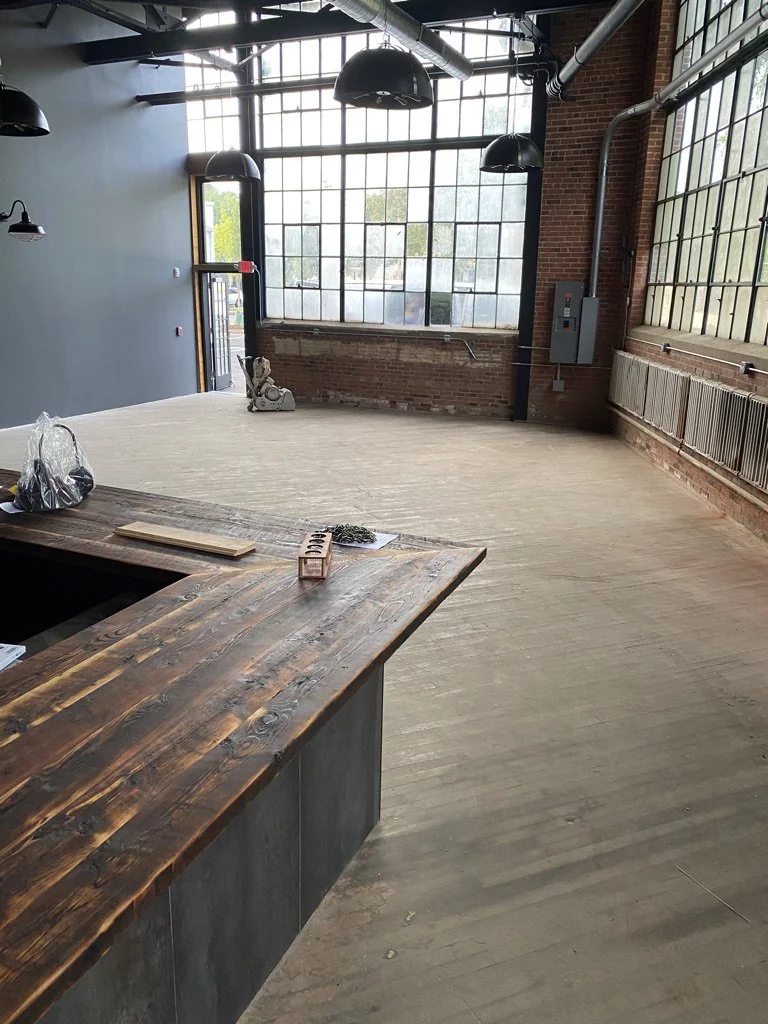 Worn gray warehouse floor before refinishing, with a floor sander by the windows, Norwalk, CT