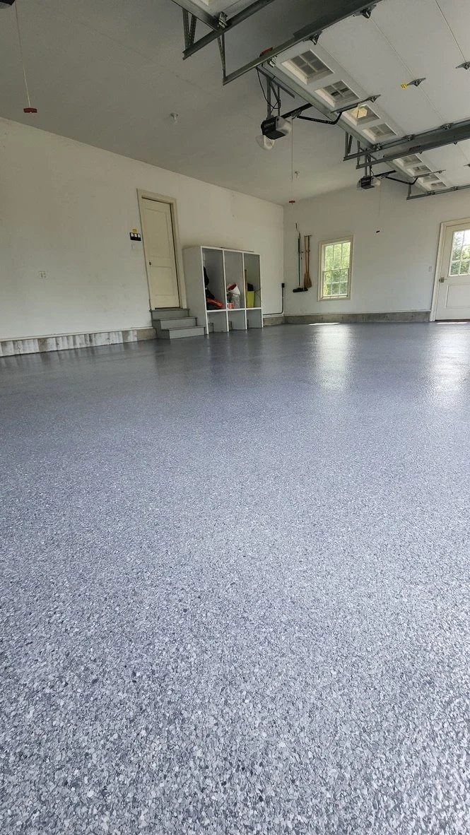 Close-up of black, white, and grey epoxy flakes being applied to a garage floor in Stamford, CT