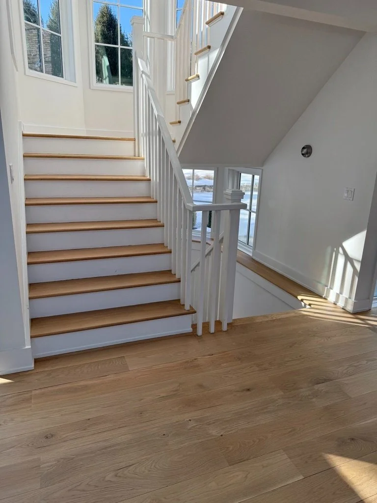 Overhead view of a wide-plank white oak staircase installation above a black wire-frame table in a modern Danbury, CT home