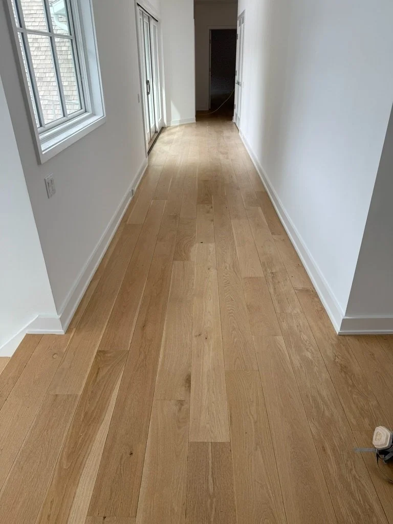 Natural finish white oak hardwood flooring in a sunlit room with floor-to-ceiling windows overlooking a snowy yard, Danbury, CT