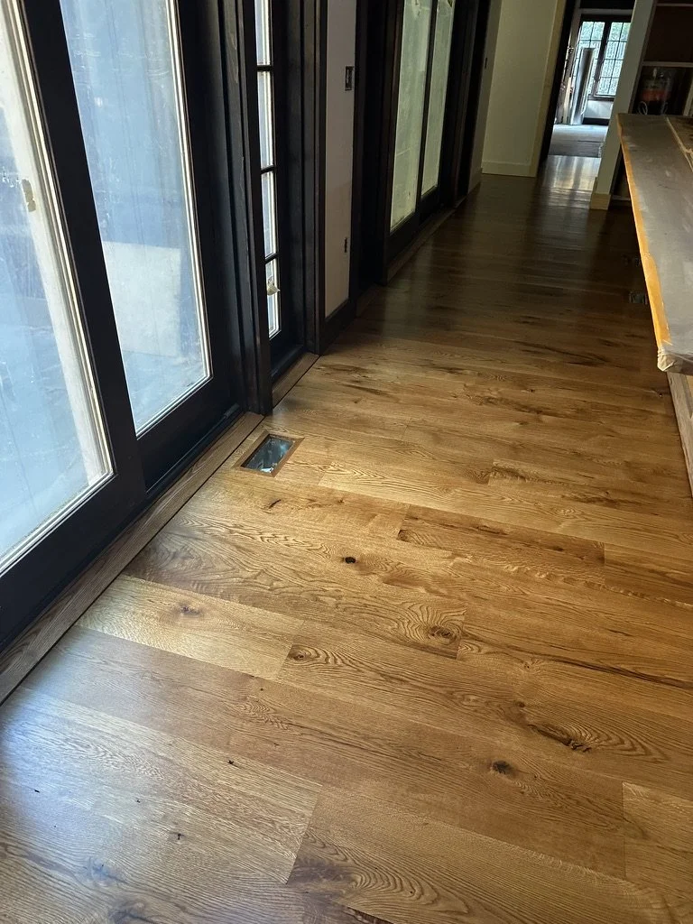 Bright entryway with new character-grade white oak flooring and a wood-paneled front door in Weston, CT