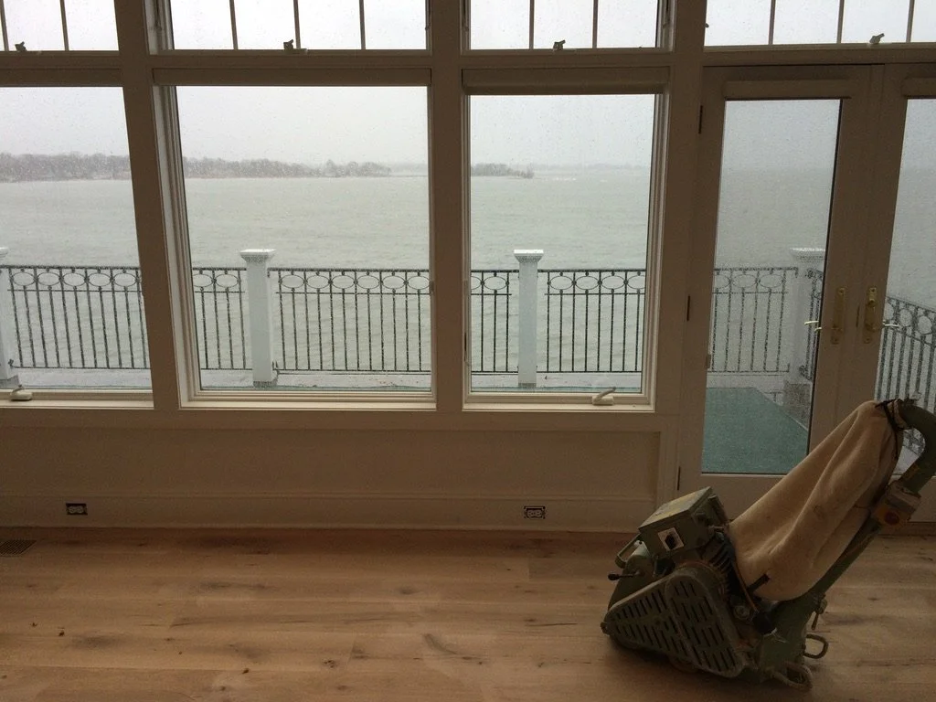 Finished white oak hardwood floor in a Stamford, CT living room with a fireplace, opening to a water-view sunroom