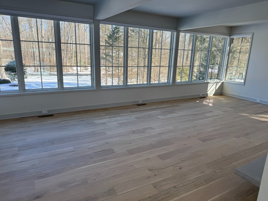 Wide-plank clear-grade white oak hardwood flooring installed through an open-concept entry and living space in a modern Danbury, CT home