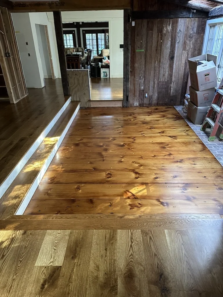Sunlight across a medium brown wide-plank white oak floor in a finished Weston, CT bedroom