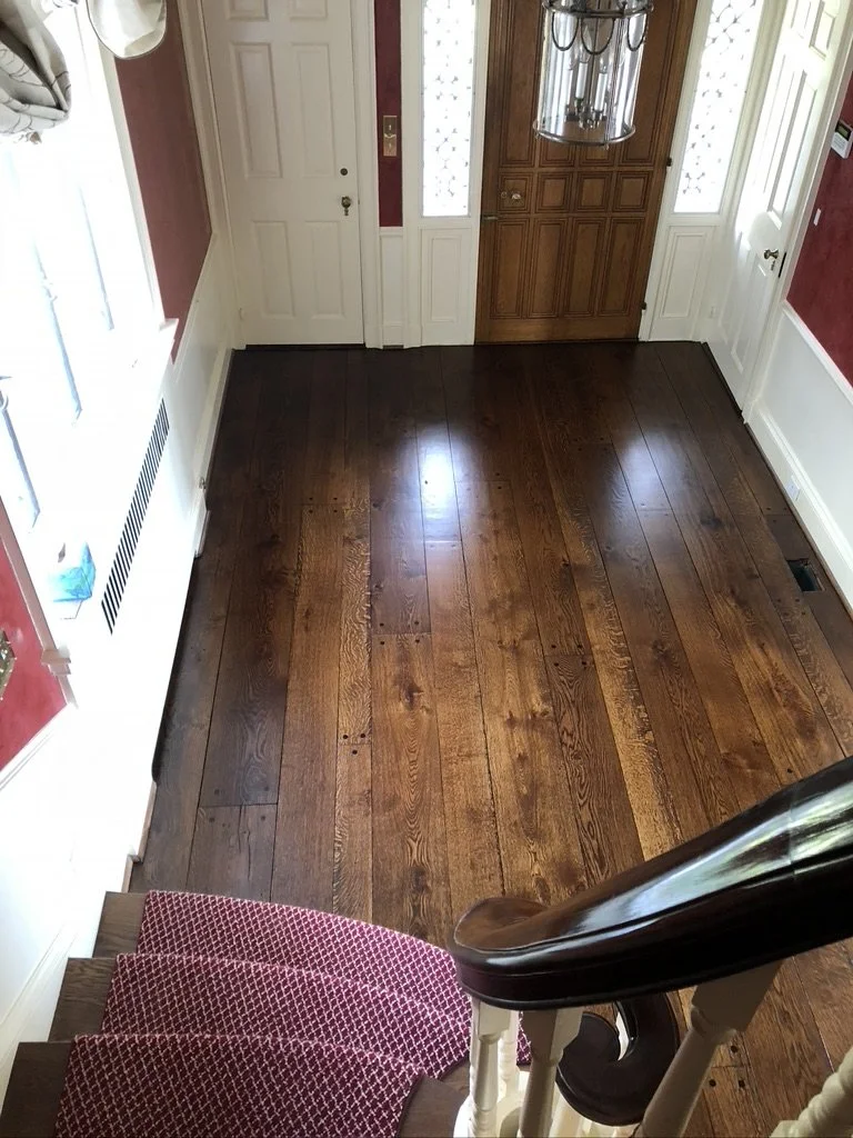 View from the staircase of a refinished dark-stained wide-plank oak foyer floor, Stamford, CT