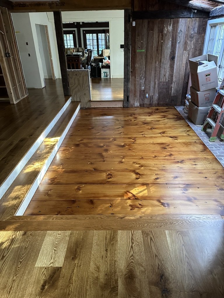 Hallway with wide-plank white oak floor installation along large windows in a Weston, CT home