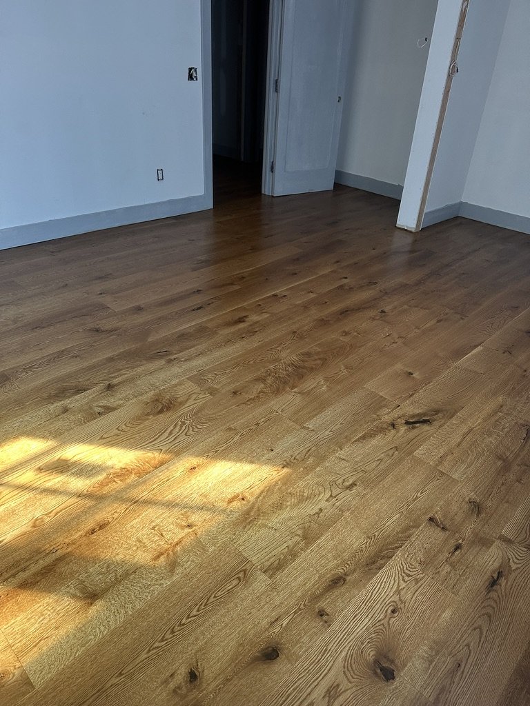 Medium brown stained wide-plank white oak floor in an empty Weston, CT bedroom after installation