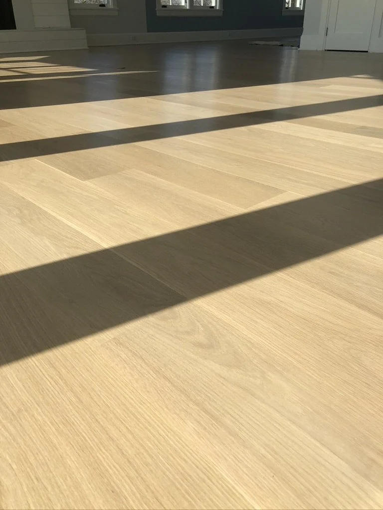 Wide view of natural white oak hardwood flooring in a sunlit, unfurnished Stamford, CT room with water views
