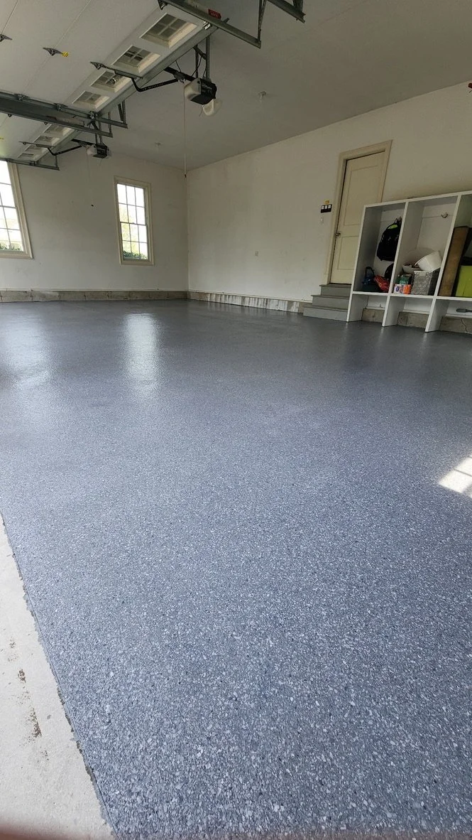 Finished epoxy flake garage floor in a white-paneled garage with a built-in storage cubby, Stamford, CT