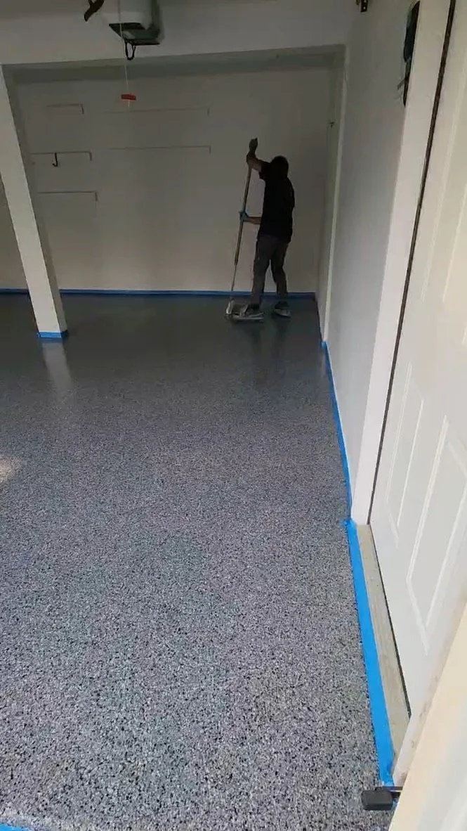 Worker troweling and smoothing an epoxy flake broadcast near a taped-off doorway during a Stamford, CT garage flooring project