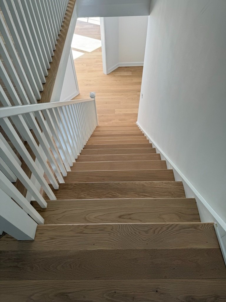 Wide-plank white oak stair treads with white painted risers on a two-story staircase with a window seat landing, Danbury, CT