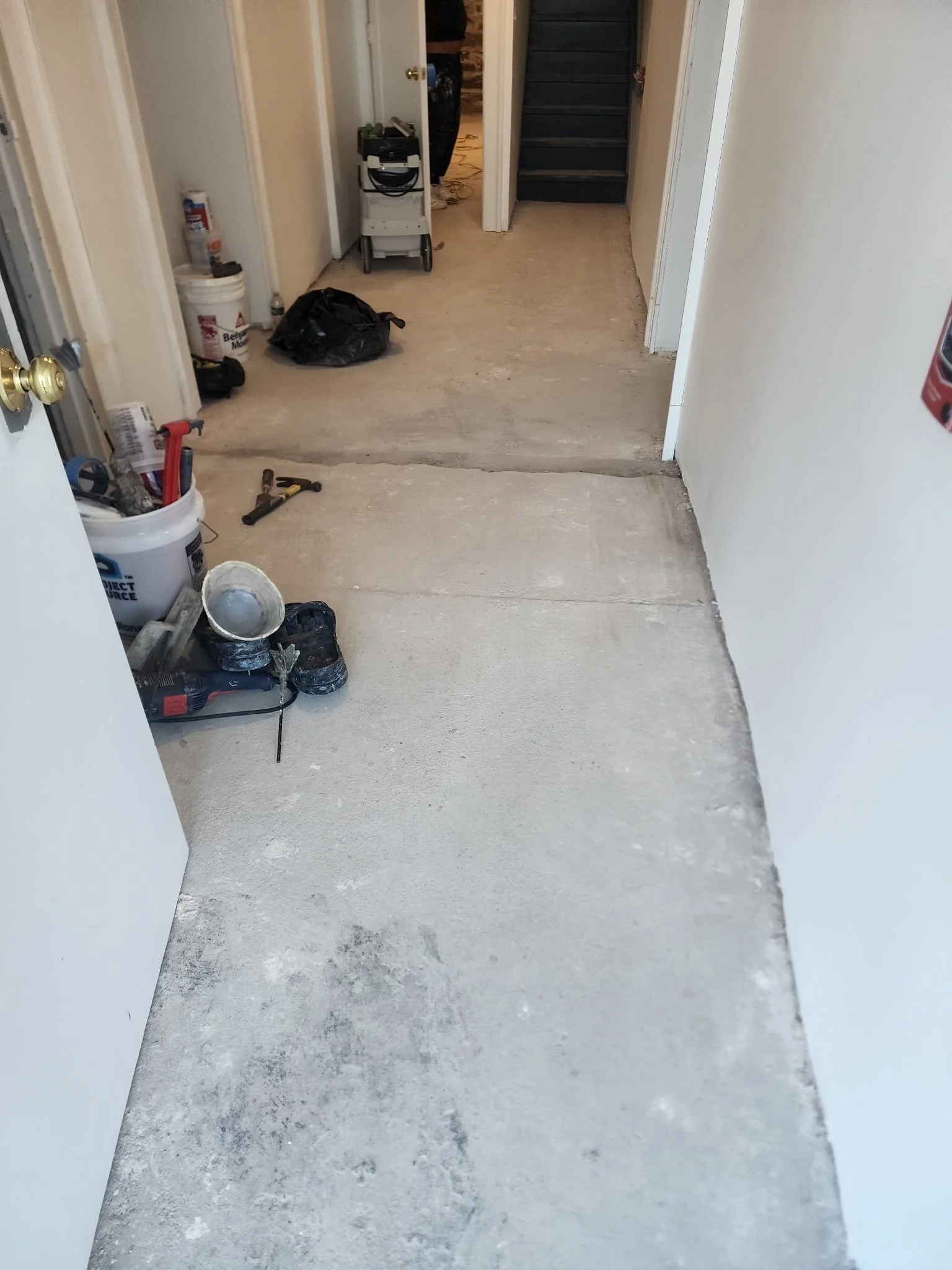 Basement corridor with dust-extraction equipment staged before epoxy coating, Danbury, CT