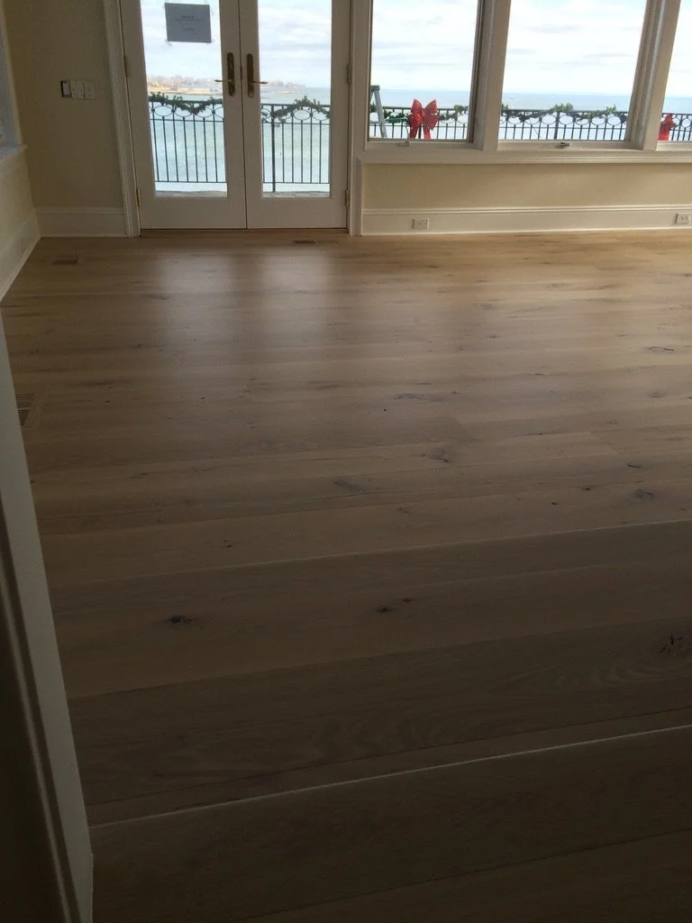 Wide-plank white oak hardwood floor in a Stamford, CT family room with a water-view deck visible through French doors