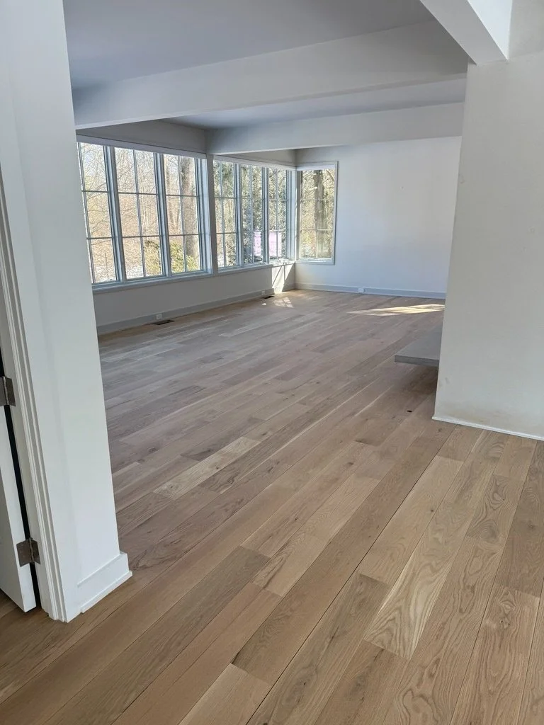 Natural finish white oak hardwood flooring in a bright room with tall windows overlooking bare winter trees, Danbury, CT installation project