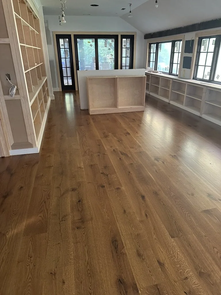 Old reclaimed wide-plank wood floor transitioning into new white oak installation near an exposed brick wall in a Weston, CT home