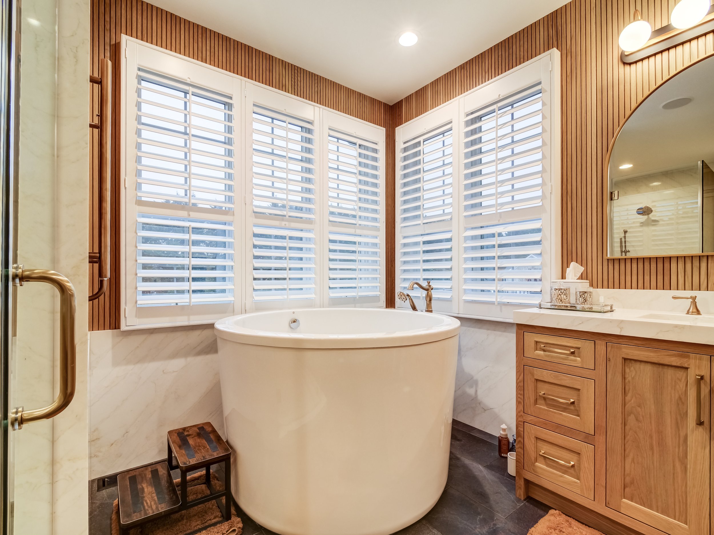 Completed bathroom remodel showing soaking tub, custom paneling and window blinds