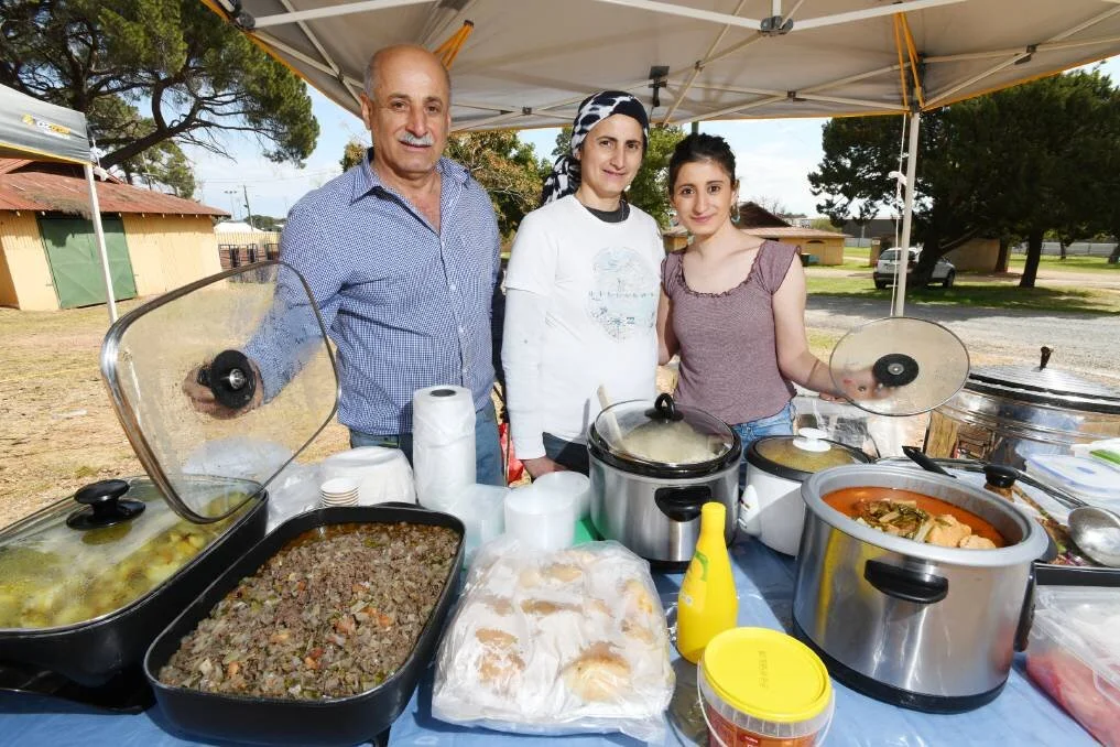 TASTE OF HOME: Kamal Gundor, Nazi Perabo and Diyana Gundor at their food stall at the Riverina Producers' Market. Utilising the powerful language of food, one Yazidi family have built a life for themselves in Wagga.It's almost that time of year where residents and visitors can eat dishes from around the world to their heart's content. In the spirit of the upcoming Fusion Festival, The Daily Advertiser is profiling some of the delicious cuisines that can be found in this city, and the people who can cook them with their eyes closed. Diyana Gundor and her family arrived as refugees to Wagga in 2017 as part of a wave of Yazidi refugees to arrive in Australia following a campaign of genocide by ISIS in Northern Iraq. An avid cook, Ms Gundor built her confidence to the point where she was able to open a food stall at the weekly Riverina Producer's Market, selling their traditional flatbread among other dishes. "We make the bread with flour and yeast and salt and leave it for one day," she said."After that, we roll it out and put in the oven."Ms Gundor and her loved ones had to flee their homes as the Yazidi people were being murdered. "My family wasn't safe in Iraq," she said. "Lots of our family and friends were killed by ISIS. "It is great living in Australia, and I love it here, thank you so much to everyone."On the menu at their stall is often Middle Eastern chicken, dolma, chickpea soup and other delicious, traditional dishes. Belinda Crain, CEO of the Multicultural Council, said Ms Yamak is just one of the community members who they have helped to set up a business at the Riverina Producers' Market that runs every Thursday at the Wagga Showgrounds.
