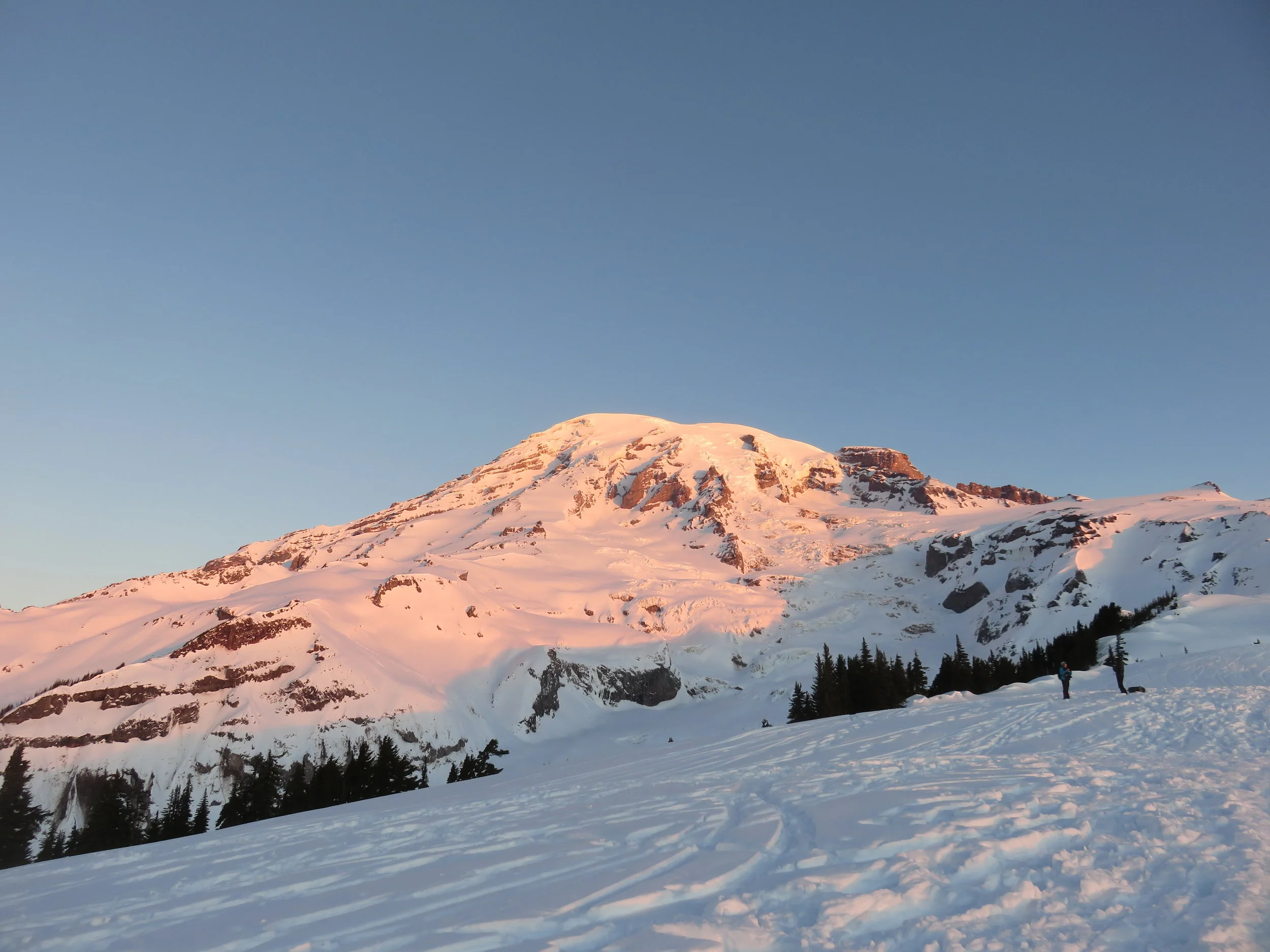 Snow covered mountain at sunrise against a blue sky