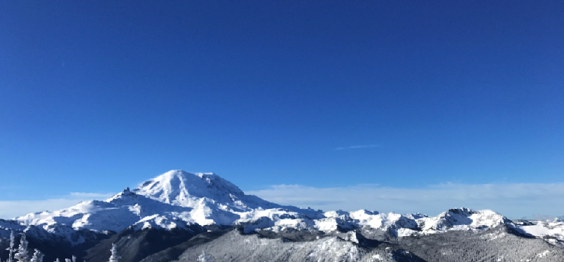 A snow covered mountain in winter against a blue sky.