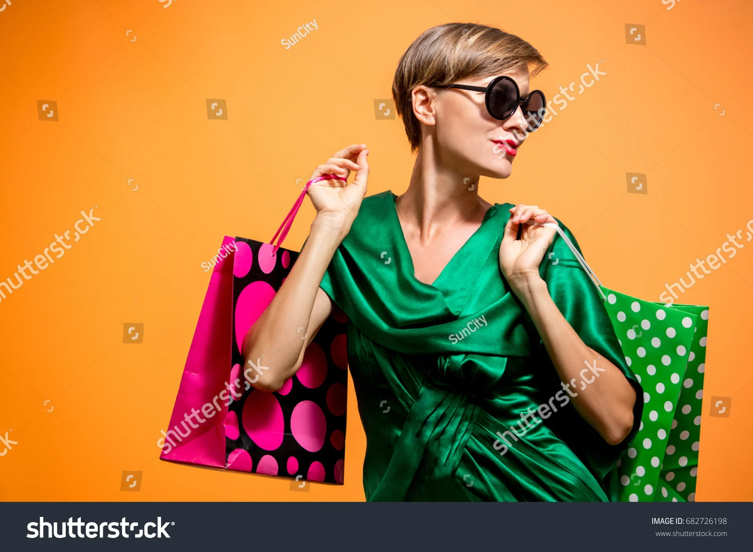 stock-photo-young-happy-summer-shopping-woman-with-shopping-bags-looking-sideways-isolated-over-bright-orange-682726198.jpg