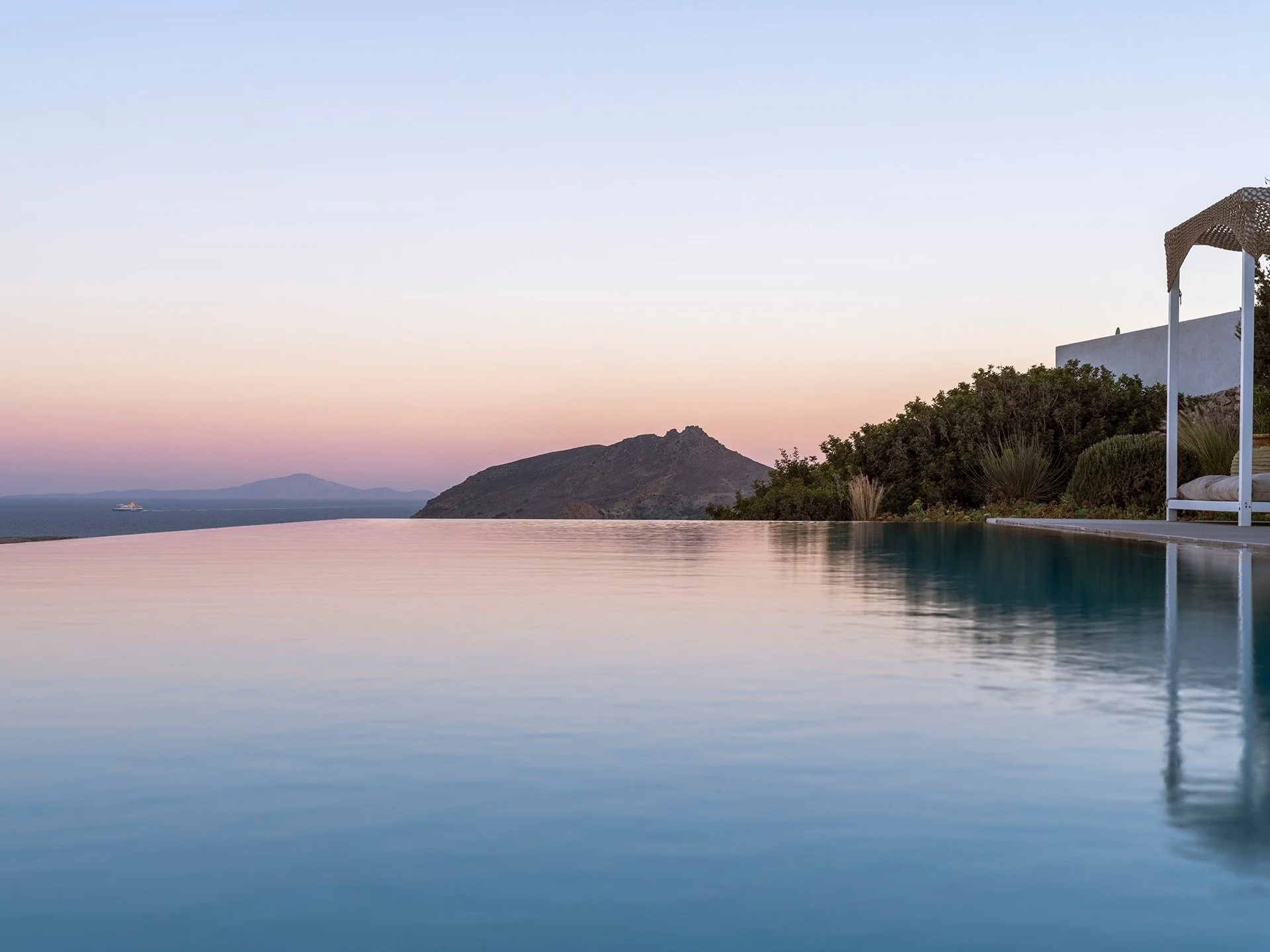 Perched above the Aegean in Ysterni, this exceptional six-bedroom villa captures the essence of high-end summer living in Paros. Designed for effortless indoor-outdoor flow, the residence opens to sweeping panoramic sea views that stretch endlessly f