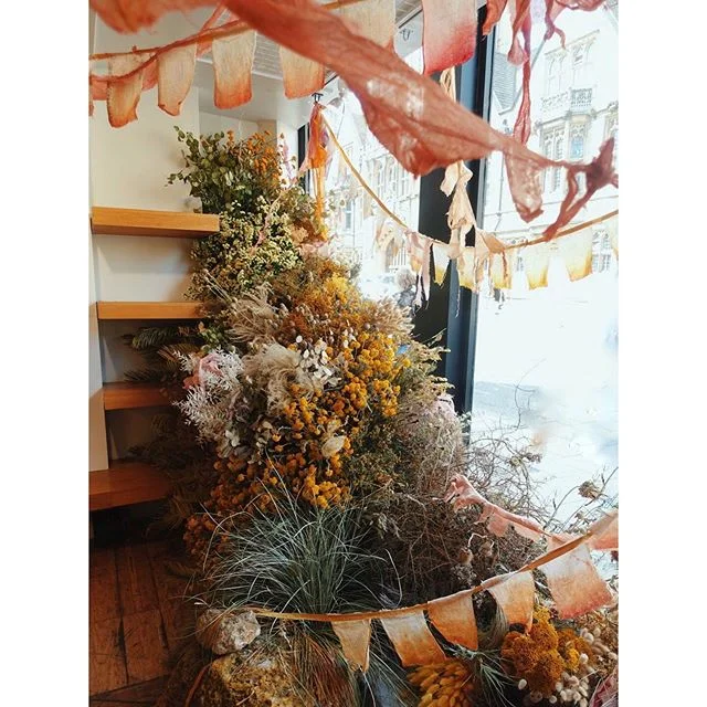 Yesterday we spent the day in @toast Oxford installing a dried flower piece based around the theme of the Pioneer. We took inspiration from artists such as Eva Hesse and Barbara Hepworth and created this summit in the window of the shop. This was another collaboration with our lovely friend @kristinperers who painted and draped the beautiful prayer flags wrapped throughout the installation. 
It&rsquo;s there for a month so if you are in the area go explore it and see some of the interesting artifacts buried beneath from the window side. There are also dried bunches wrapped in a prayer flag on sale inside the store. More information on the collaboration is linked in our bio. #TOASTxWORM