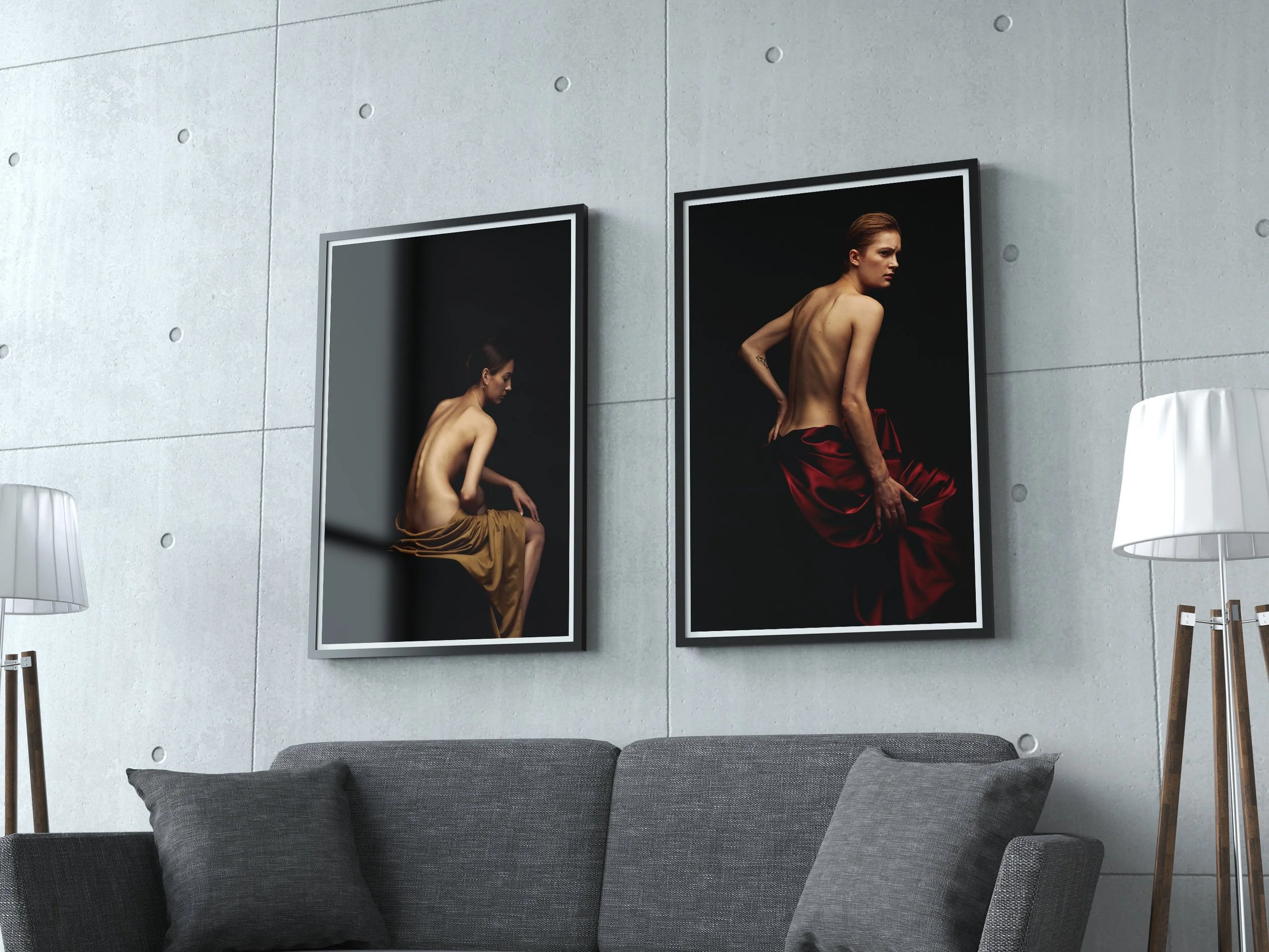 Two framed photographs of a topless woman with a tattoo on her forearm, wearing red skirt, are hung on a light gray wall in a modern room. Beside them are two white lamps and a gray couch with cushions.