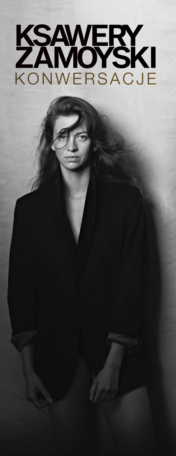 Book cover featuring a black-and-white photograph of a woman with long messy hair wearing a dark blazer. The title reads "KSAWERY ZAMOYSKI KONwersacje" in large bold letters at the top.
