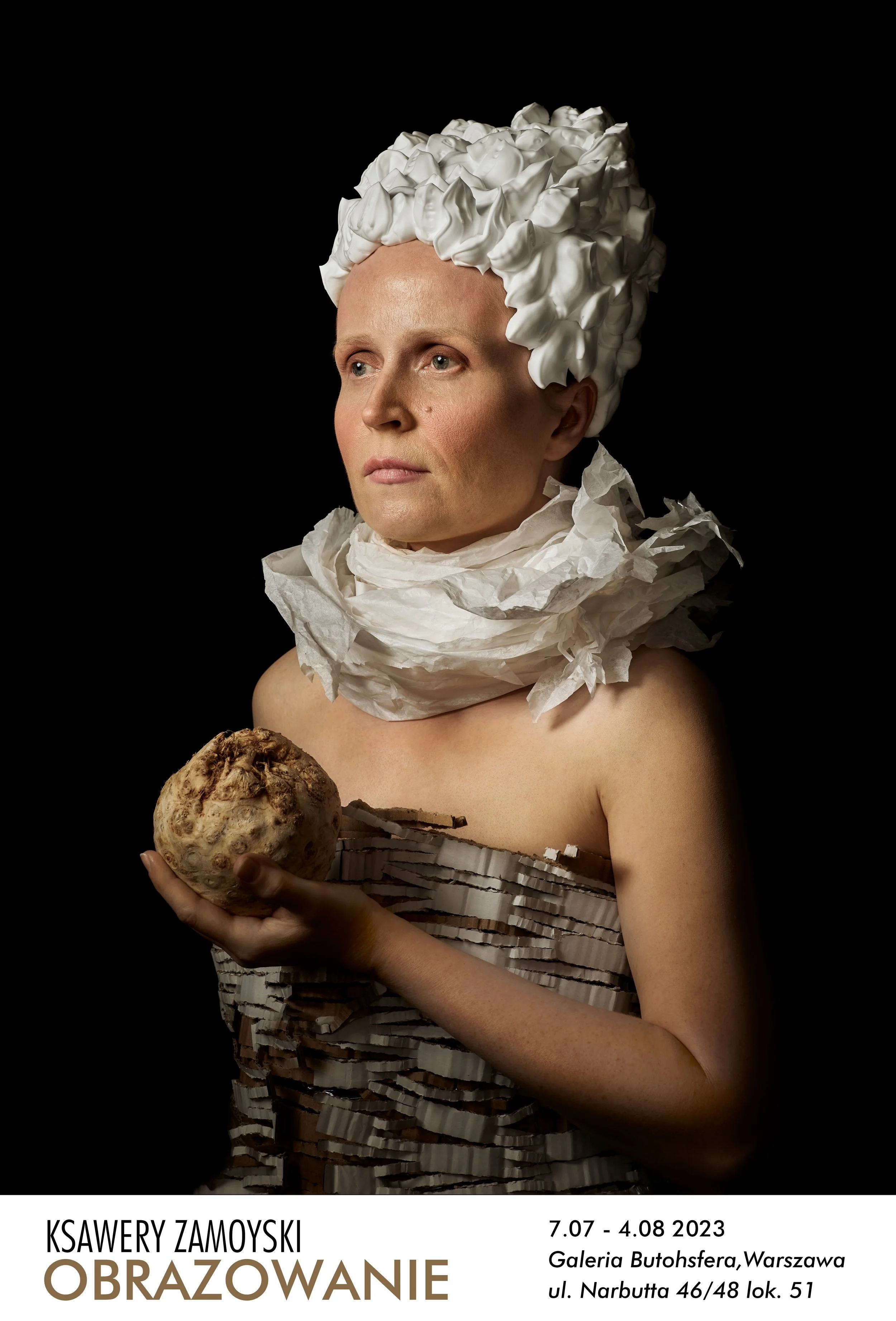 A woman with an elaborate white headpiece and scarf made of crumpled paper, holding a large root vegetable against a black background, promoting an art exhibition.