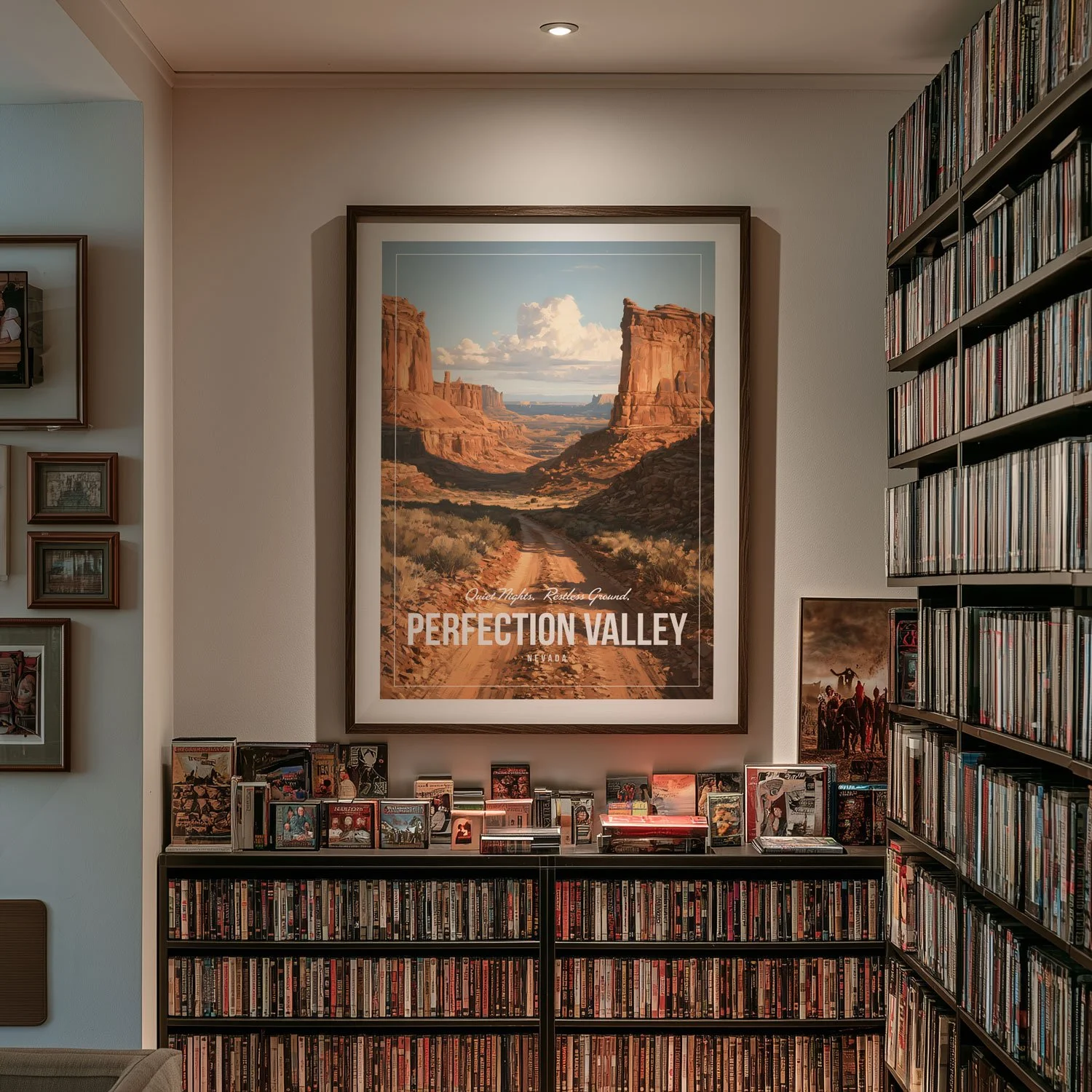 An A1 frame holding a 20x30-inch poster of Perfection Valley hangs on a white wall above shelves filled with DVDs. The artwork on our poster is inspired by the movie "Tremors".