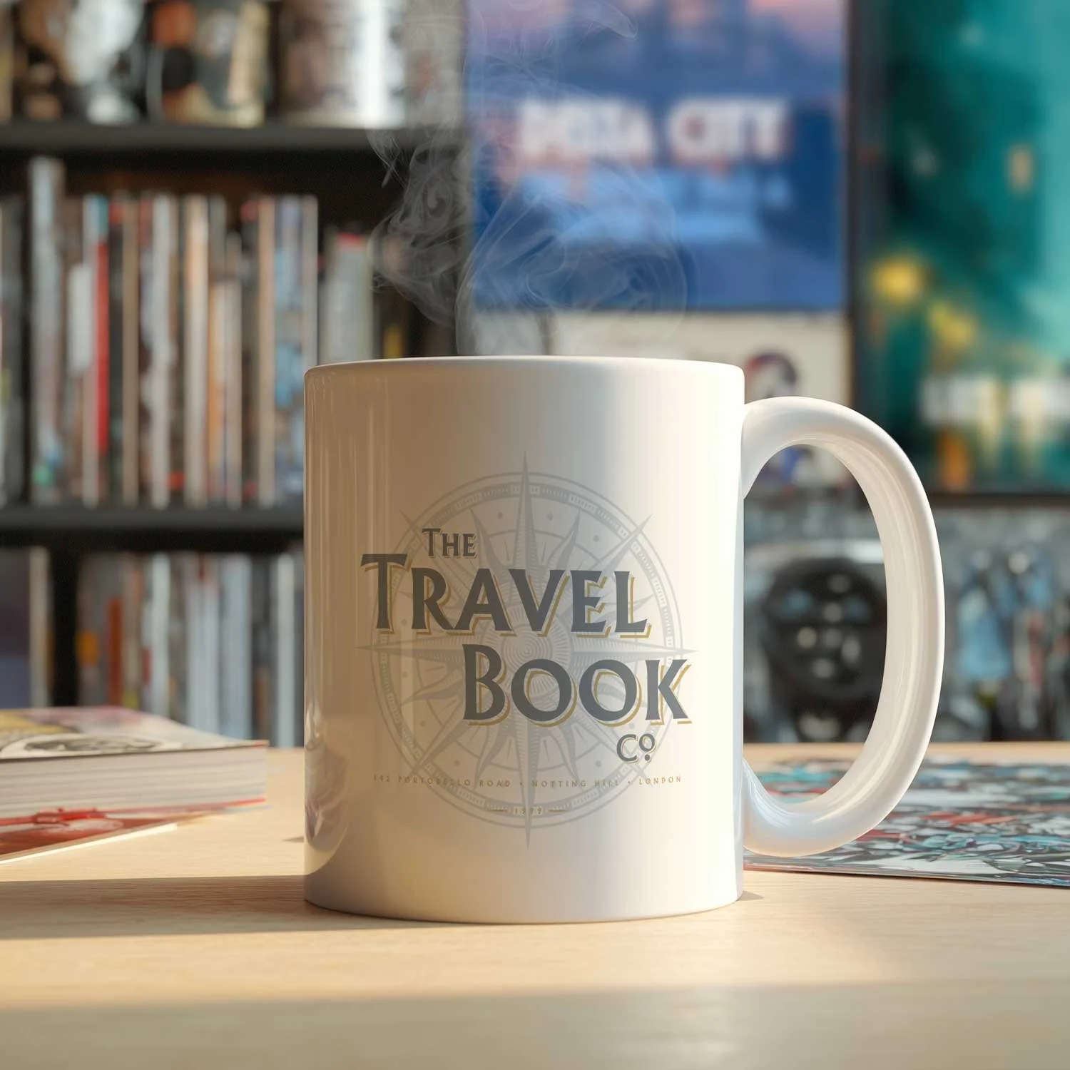 A Travel Book Co mug is displayed on a table, filled with coffee.