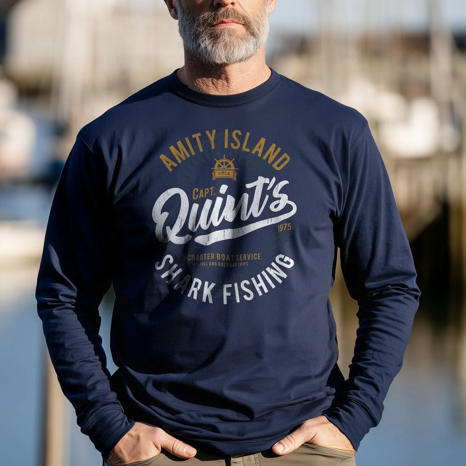 Image of a man wearing a Quint's Shark Fishing long-sleeve T-shirt in a rugged New England harbor.