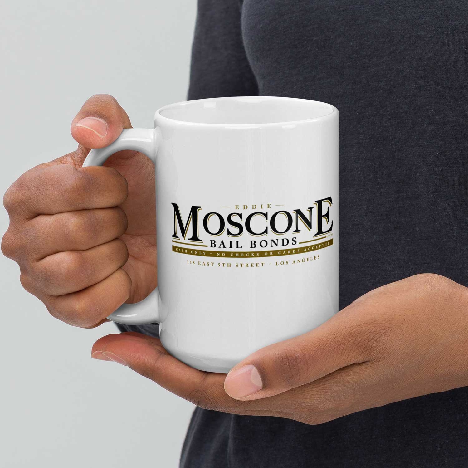 Close-up of a man holding a 15-oz Moscone Bail Bonds Mug.