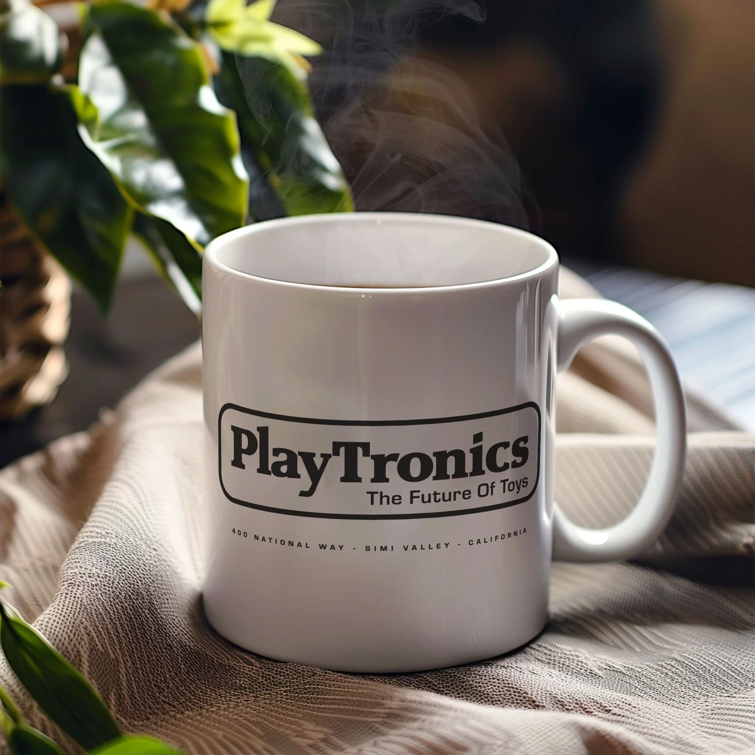 A PlayTronics mug is displayed on a table, filled with coffee.